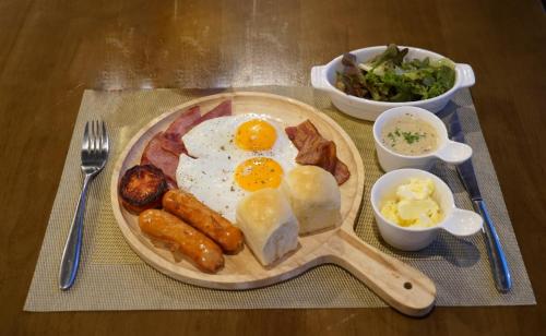 a plate of breakfast food with eggs sausage and bacon at VARIMANTRA HOTEL in Nakhon Pathom