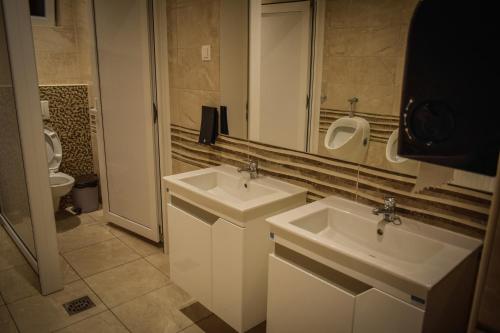 a bathroom with two sinks and a toilet and a mirror at Garni hotel Mali predah - novi deo in Knjazevac.