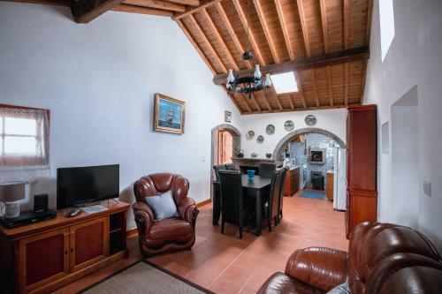 a living room with leather chairs and a table with a television at Sete Cidades House in Sete Cidades