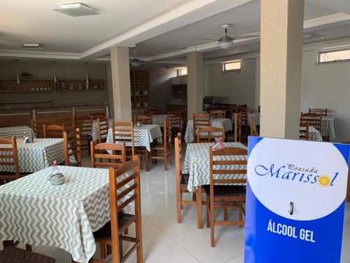 un comedor con mesas y sillas y un cartel en Pousada Marissol, en Cabo Frío