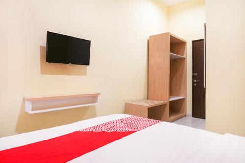 Un dormitorio con una cama y un televisor en la pared. en Hotel O DeHome Family, en Yogyakarta