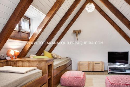 a attic bedroom with two beds and a tv at Casa Er Os by Totiaran in Baqueira-Beret
