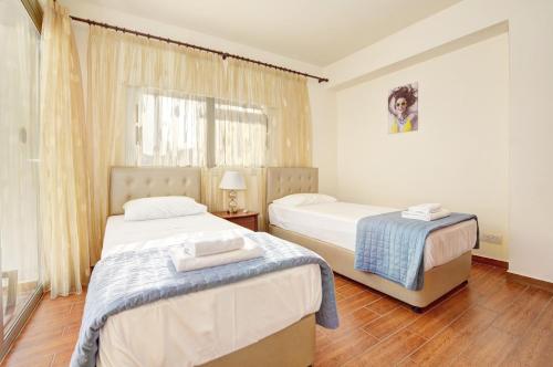 a bedroom with two beds and a window at Seafront Protaras Apartments in Protaras