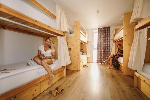 a woman sitting on a bed in a room with bunk beds at We Hostel Palma - Albergue Juvenil in Palma de Mallorca
