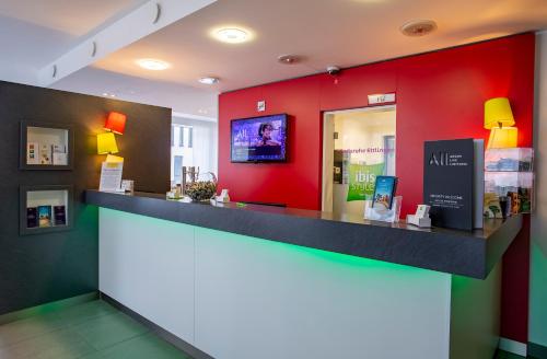a store with a red wall and a counter at ibis Styles Karlsruhe Ettlingen in Ettlingen