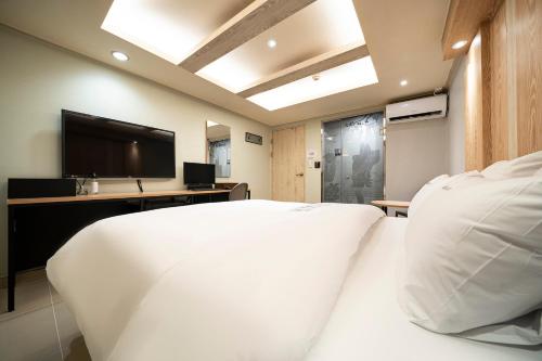 a bedroom with a white bed and a flat screen tv at Suwon Sunstar Hotel in Suwon