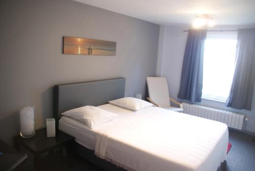 a bedroom with a large white bed and a window at Vakantie Logies Allo Allo in Poperinge