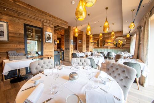 een eetkamer met witte tafels en stoelen bij Hotel Le V de Vaujany in Vaujany