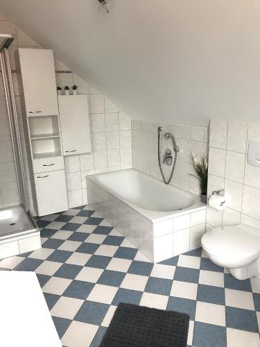a white bathroom with a tub and a toilet at Gästehaus-Après-Park in Rust