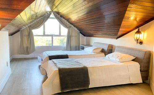 1 dormitorio con 2 camas y ventana en Letto Hotel Flores da Cunha, en Flores da Cunha