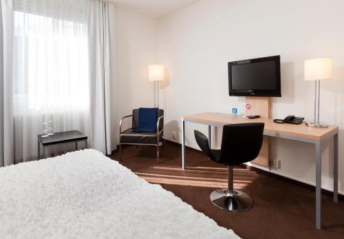 Schlafzimmer mit einem Bett, einem Schreibtisch und einem TV in der Unterkunft Hotell Charlottenberg in Charlottenberg