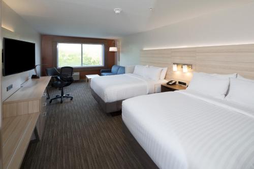 a hotel room with two beds and a flat screen tv at Holiday Inn Express & Suites - Kalamazoo West by IHG in Kalamazoo