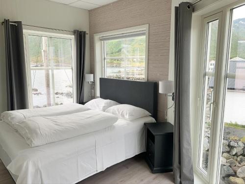 a bedroom with a white bed and two windows at Mefjord Brygge in Mefjordvær
