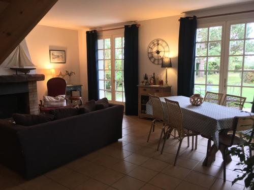 ein Wohnzimmer mit einem Sofa, einem Tisch und Stühlen in der Unterkunft Le Lodge des Prés in Eu