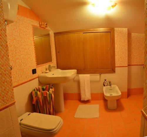 een badkamer met een wastafel, een toilet en een spiegel bij Villa Silvia in Acquasanta Terme