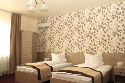 two beds in a hotel room with a wall mural at Pensiunea Rix Rooms in Focşani