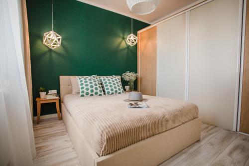 1 dormitorio con 1 cama con pared verde en W&K Apartments - Green Suite, en Koszalin