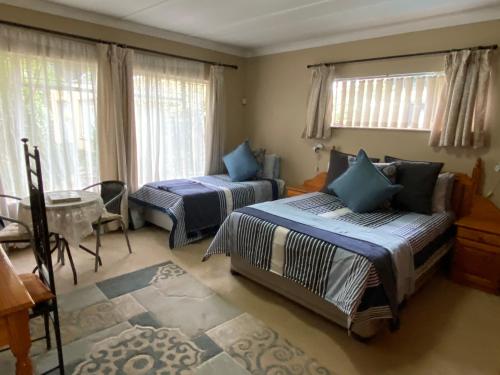 a bedroom with two beds and a table and windows at Tula@159 in Bloemfontein