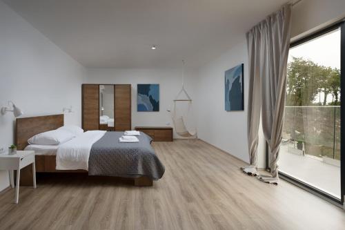 a bedroom with a bed and a large window at Infinity pool Villa San Amore in Divšići