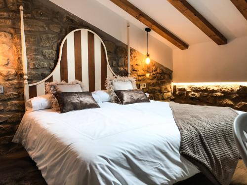 a bedroom with a large white bed with a stone wall at La Casona de Alútiz & Bodega in Samaniego