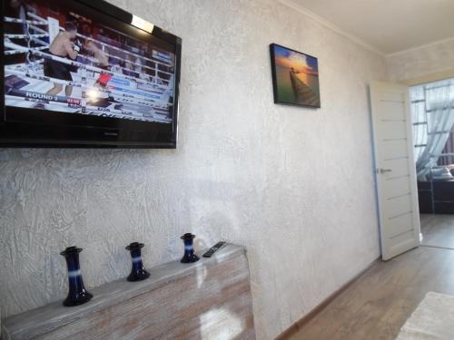 a living room with a tv on a wall with vases at Apartment WAVE,в центре! in Khmelʼnytsʼkyy