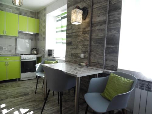 a kitchen with green cabinets and a wooden table and chairs at Apartment WAVE,в центре! in Khmelʼnytsʼkyy