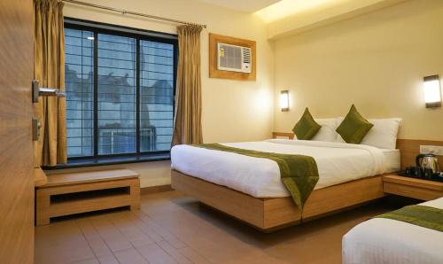 a hotel room with two beds and a window at Rahi Plaza in Mahabaleshwar
