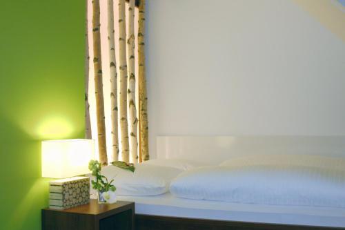 a bedroom with a white bed and a green wall at Hotel zur Promenade in Donauwörth