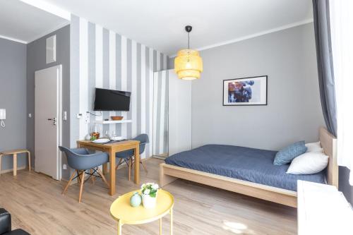 クラクフにあるFriendhouse Apartments Avenueのベッド、デスク、テレビが備わる小さな客室です。