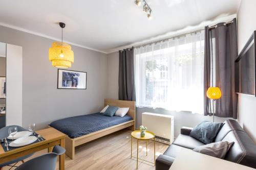 クラクフにあるFriendhouse Apartments Avenueのベッド1台とソファが備わる小さなアパートメントです。