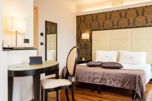 a bedroom with a bed and a desk with a laptop on it at Hotel Touring in Bologna