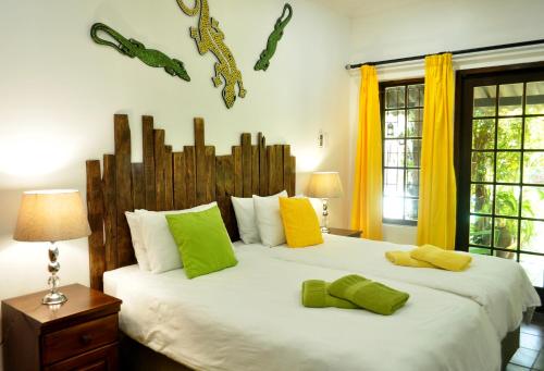 a bedroom with a large bed with green and yellow pillows at Maputaland Guest House in St Lucia