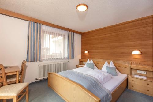 1 dormitorio con cama, escritorio y ventana en Haus Hugo, en Sölden