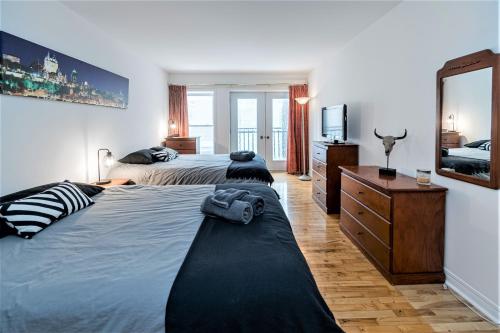 a bedroom with two beds and a dresser and a mirror at Le Théâtral - En plein coeur de l'action avec stationnement in Quebec City