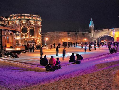 a group of people sitting on a ice rink at night at Le Théâtral - En plein coeur de l'action avec stationnement in Quebec City