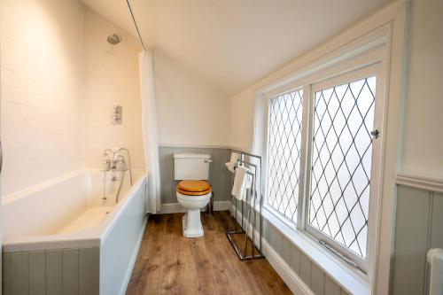 a bathroom with a toilet and a tub and a window at 6 Monkbar Court in York