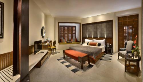 a bedroom with a bed and a chair and a desk at The Lalit Great Eastern Kolkata in Kolkata