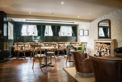a restaurant with tables and chairs and a fireplace at The Bear Of Rodborough Hotel in Stroud