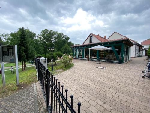 a building with a fence in front of a brick sidewalk at Ferienhof am Trift in Bad Saarow