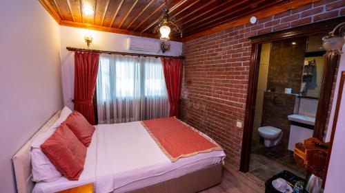 a small bedroom with a bed and a brick wall at Antalya Inn Hotel in Antalya