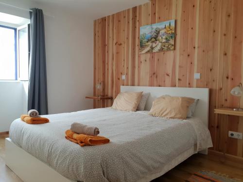 a bedroom with a large white bed with wooden walls at Casa Azul da Beija in Furnas