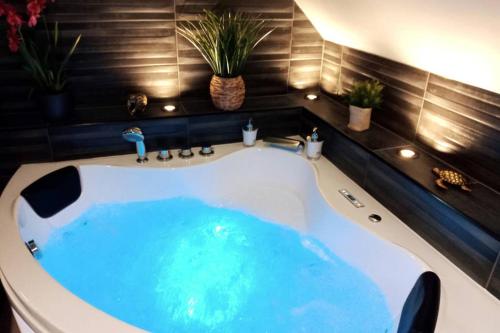 a bath tub with blue water in a bathroom at L'Evasion... Balnéo. in Sainte-Savine