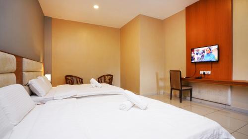 a hotel room with two beds and a flat screen tv at J.G. Resort in Pengerang