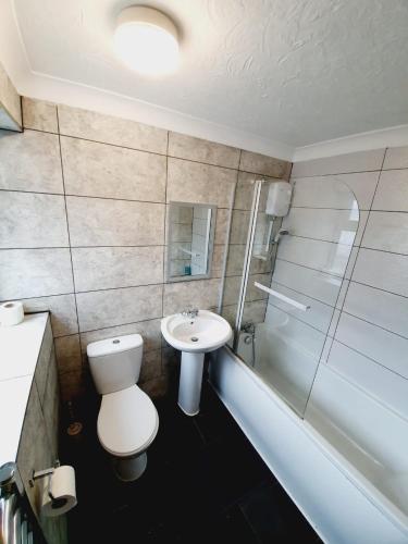 a bathroom with a toilet and a sink and a shower at 4 Bedroom Thundersley Apartment in Rayleigh