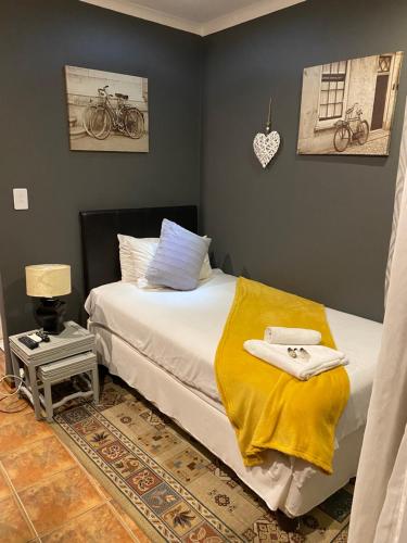 a bedroom with a bed with a yellow blanket on it at Marion Lodge in Johannesburg