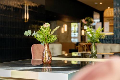 a vase filled with flowers sitting on a table at voco Paris Montparnasse, an IHG Hotel in Paris