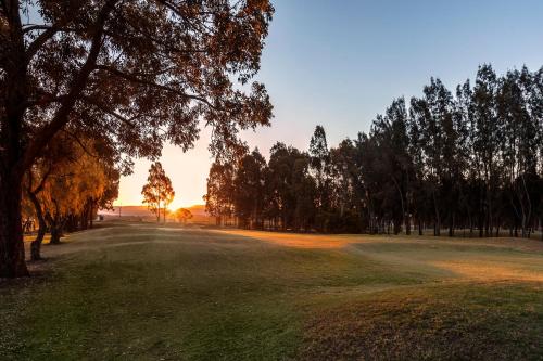 a golf course with a sunset in the background at Rydges Resort Hunter Valley in Lovedale