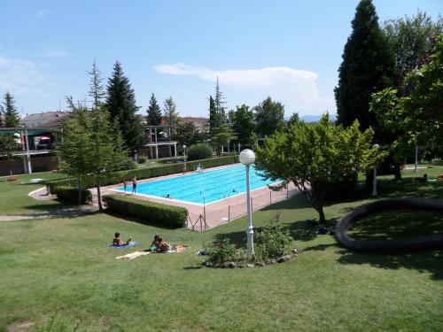 a swimming pool with people sitting in the grass at El Lagar De ElCiego in Elciego