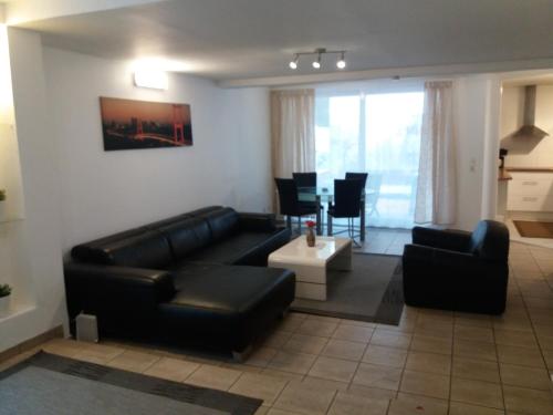 a living room with a black leather couch and a table at Appartement Confidence, Monteurwohnung in Bürstadt