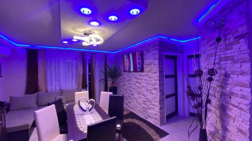 シオーフォクにあるBálint & Timi wellness apartmanの紫色の照明とレンガの壁が特徴のリビングルーム